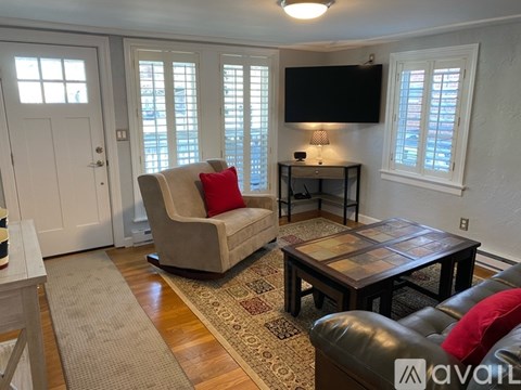 A living room with a beige chair and a black leather couch.