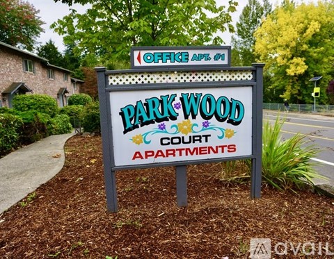 A sign for Park Wood Court Apartments is displayed in front of a building.