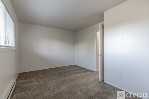 A room with a carpeted floor and a door on the right side.
