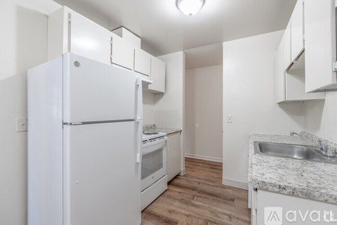 A kitchen with a white refrigerator, stove, and sink.