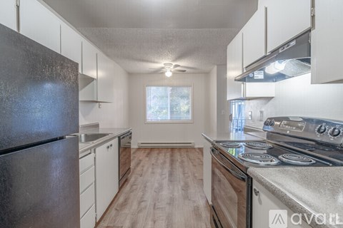 A kitchen with a black refrigerator, white cabinets, and a stainless steel stove top.