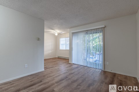 A room with wooden floors and a window with blinds.