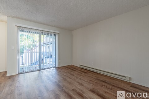 A room with wooden floors and a sliding glass door leading to a balcony.