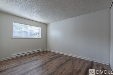 A room with wooden flooring and a window with blinds.