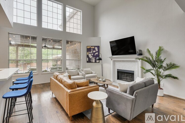 A living room with a grey couch, a white fireplace, and a television on the wall.