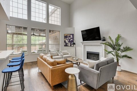 A living room with a grey couch, a white fireplace, and a television on the wall.
