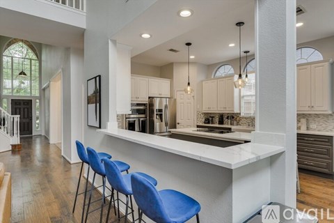 A kitchen with a white counter and blue chairs.