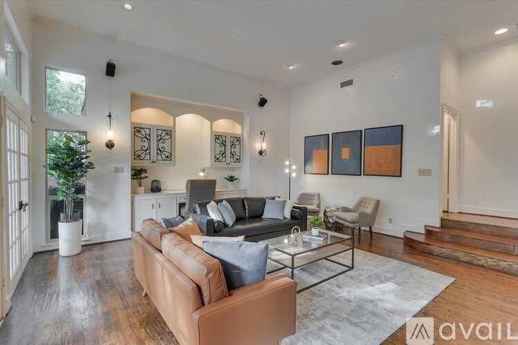 A modern living room with a brown leather couch and a glass coffee table.