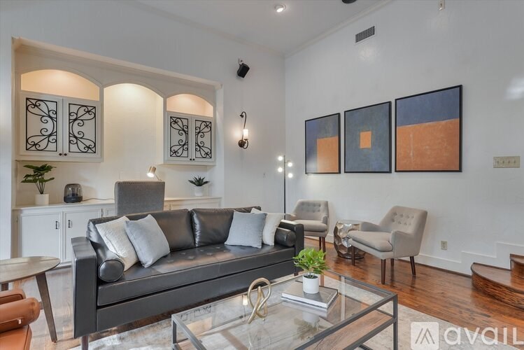 A living room with a black couch and a glass coffee table.
