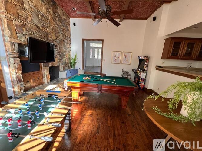 A room with a pool table, a fireplace, and a television.