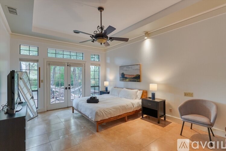 A bedroom with a bed, chair, and a ceiling fan.