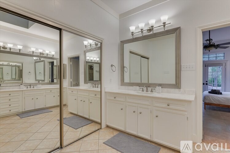 A large mirror with lights above it is in the center of a bathroom with double sinks.
