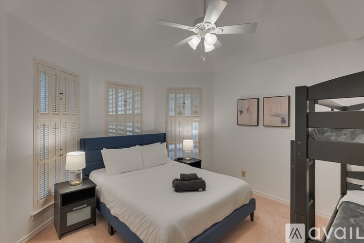 A bedroom with a bed, nightstand, and a ceiling fan.