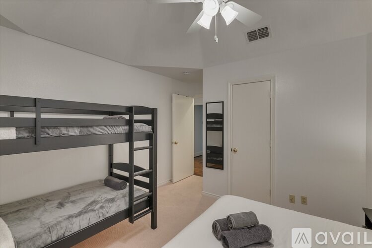 A room with a bunk bed and a ceiling fan.
