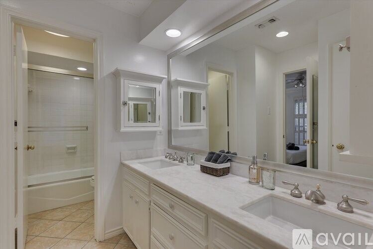 A bathroom with a large mirror, a bathtub, and a sink.