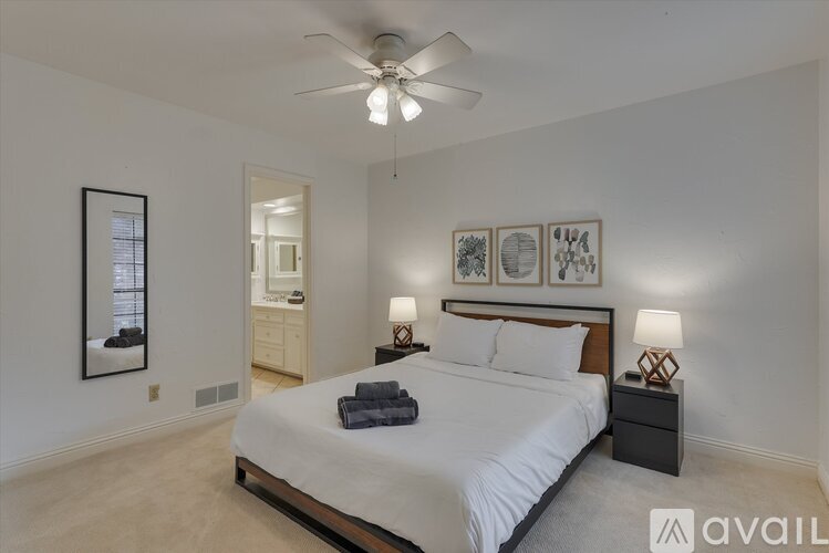 A bedroom with a large bed, a ceiling fan, and a mirror on the wall.