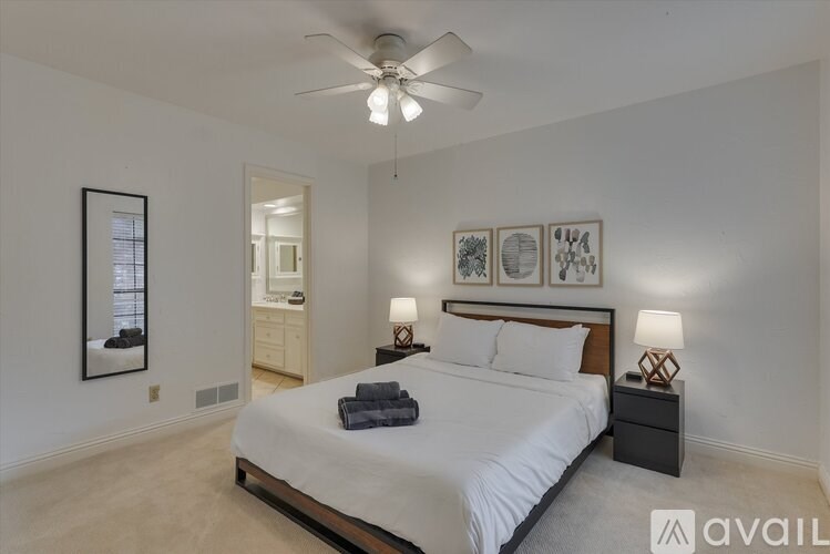 A bedroom with a large bed, a ceiling fan, and a mirror on the wall.