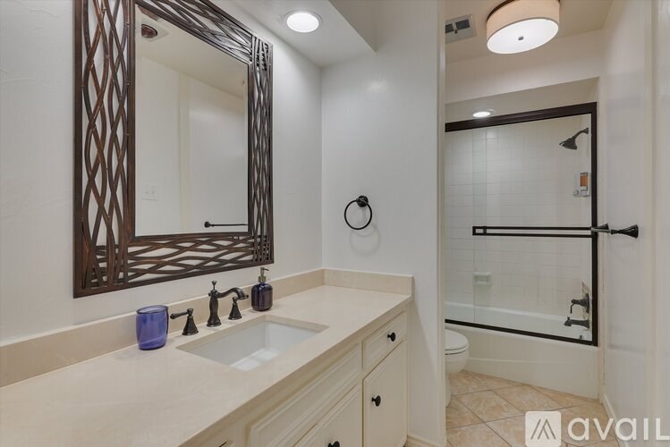 A bathroom with a sink, mirror, and shower.