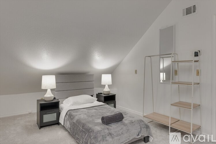 A bedroom with a bed, two lamps, and a shelf.