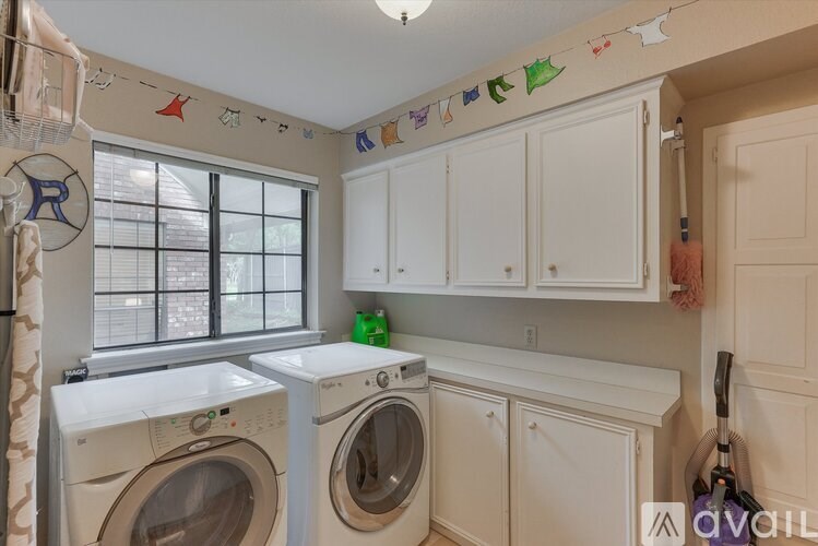 A laundry room with a washer and dryer, a window, and a wall with decorations.
