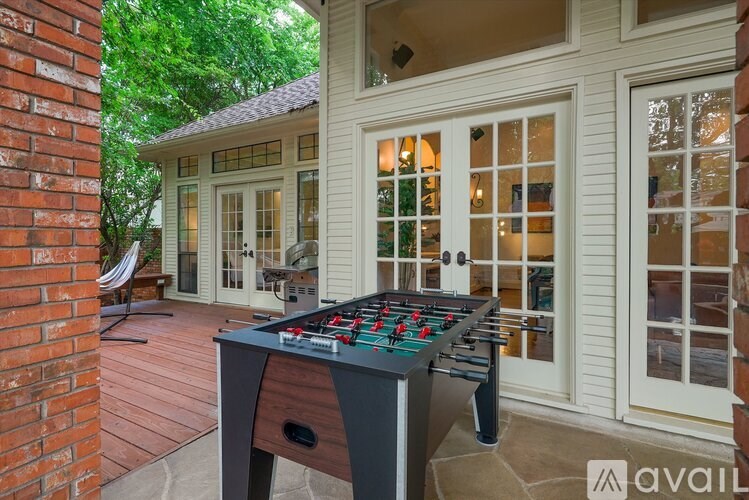 A foosball table is on a wooden deck outside a house.