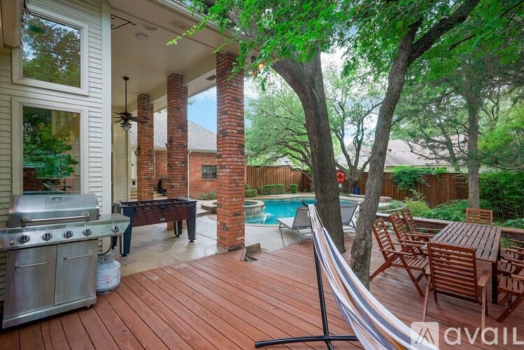 A patio with a table and chairs is surrounded by trees.