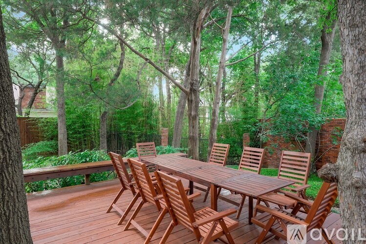 A wooden table and chairs set up on a deck in a wooded area.
