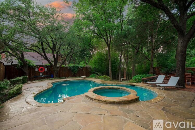 A backyard with a pool and a stone patio.
