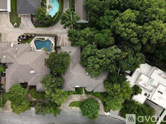A bird's eye view of a residential area with houses, trees, and a pool.