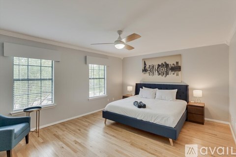 A bedroom with a bed, a chair, and a ceiling fan.