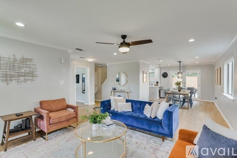 A living room with a blue couch and a glass coffee table.