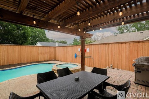A patio with a table and chairs and a pool.