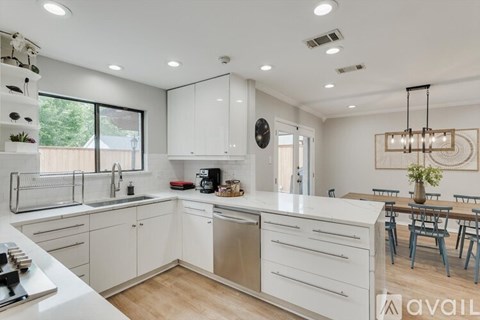 A modern kitchen with white cabinets and a wooden floor.