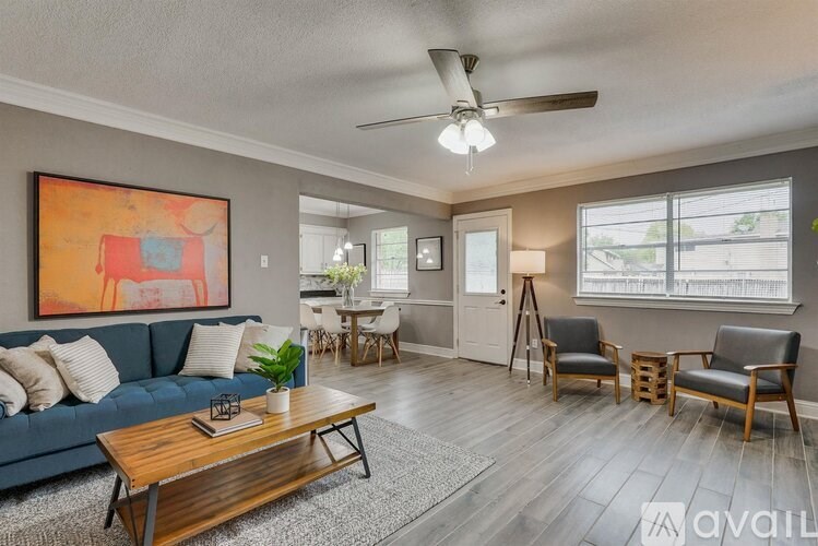 A living room with a blue couch, a wooden coffee table, and a ceiling fan.