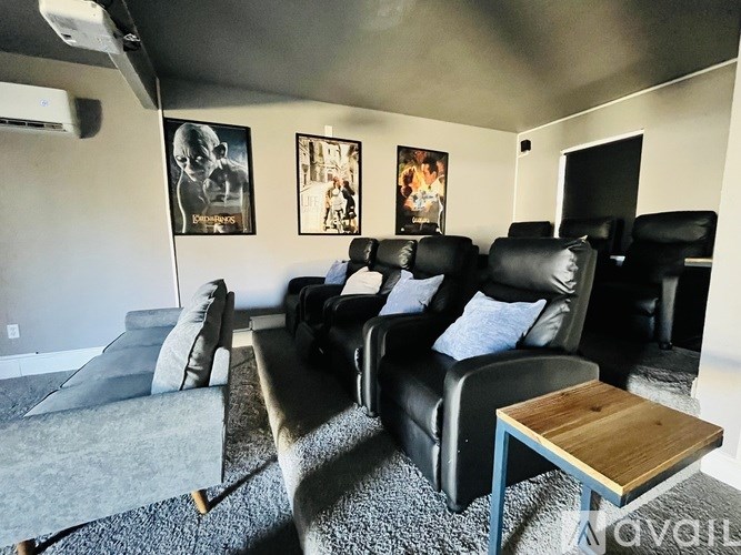 A living room with black leather couches and a grey carpet.