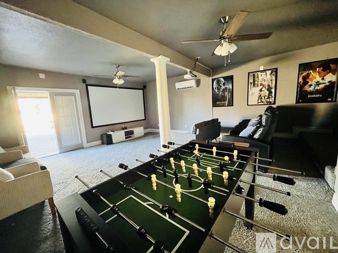 A foosball table is in the middle of a room with a couch and a TV.