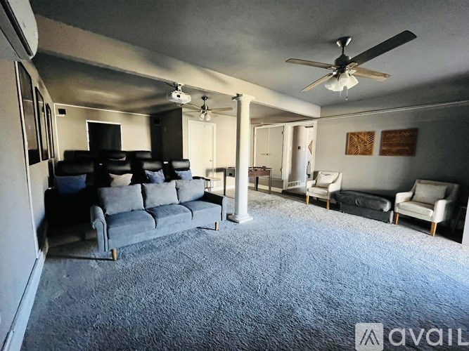 A living room with a grey carpet and a grey sofa.