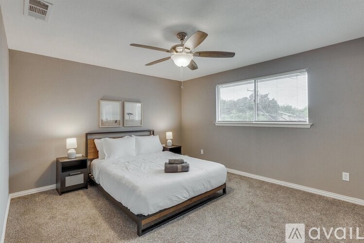 A bedroom with a bed, nightstands, and a ceiling fan.