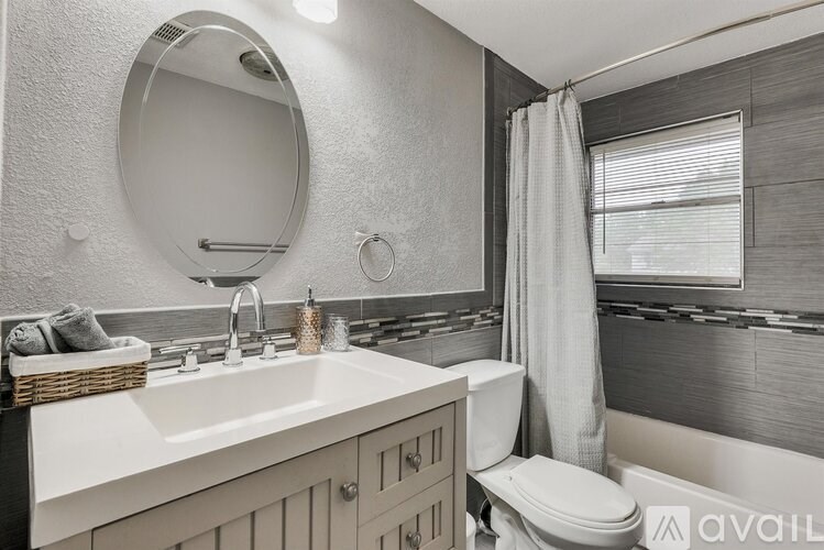 A bathroom with a white sink, toilet, and a round mirror.