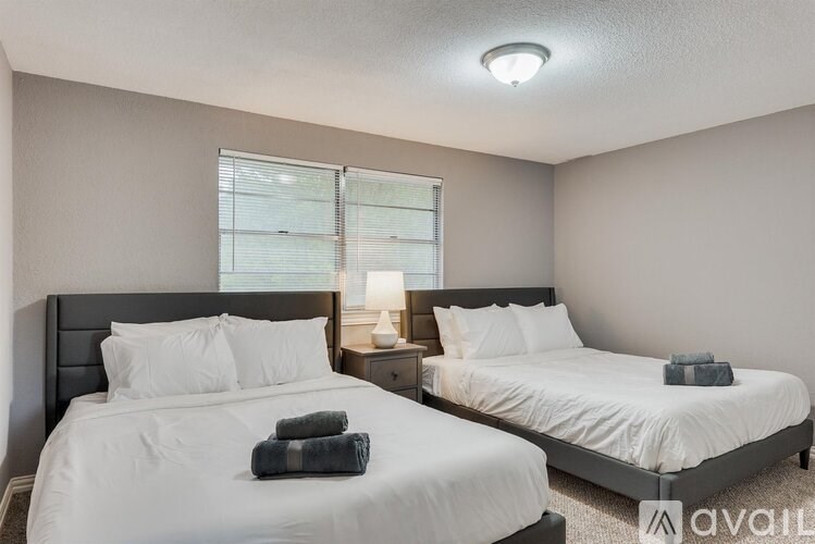 Two twin beds with white bedding and pillows in a room with a window.