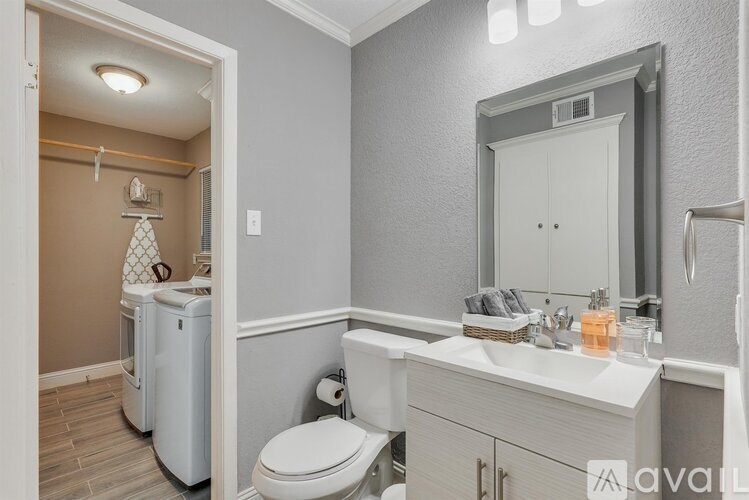 A bathroom with a toilet, sink, and mirror.
