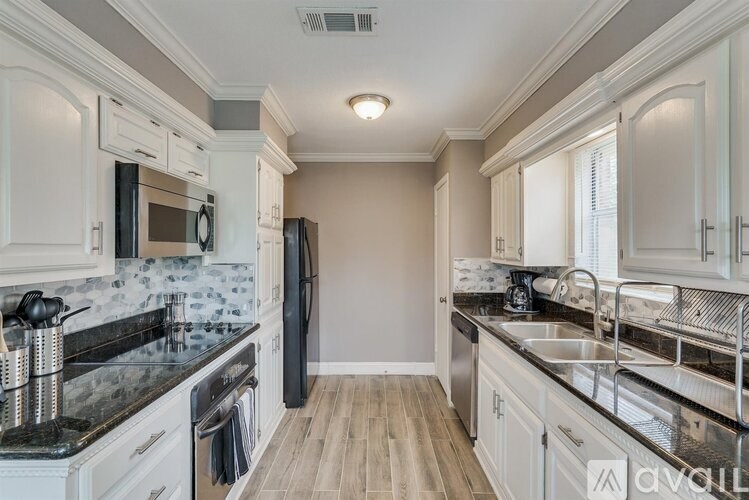 A kitchen with black appliances and white cabinets.