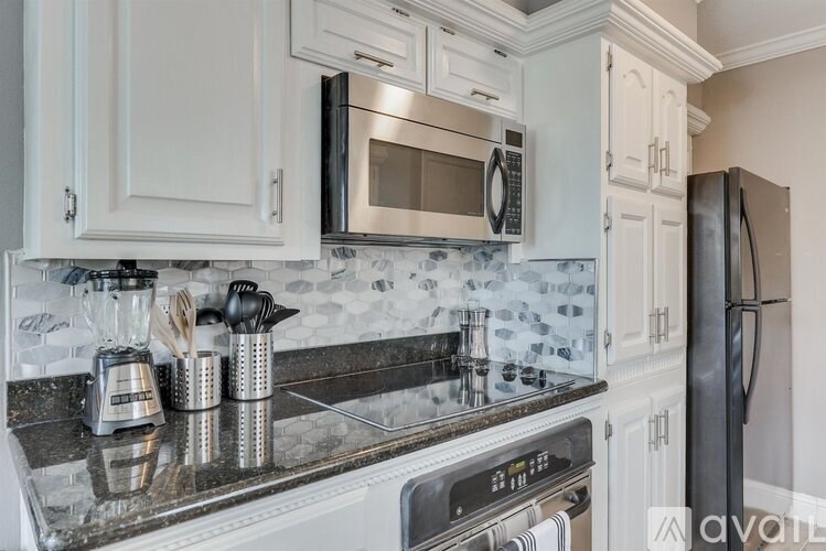 A kitchen with a black refrigerator and a black microwave above a stove.