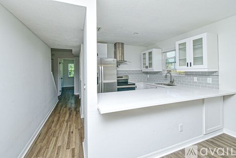 A kitchen with white cabinets and a wooden floor.