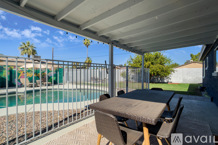 A patio with a table and chairs overlooking a pool.