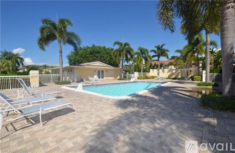 A pool surrounded by palm trees and sun loungers.