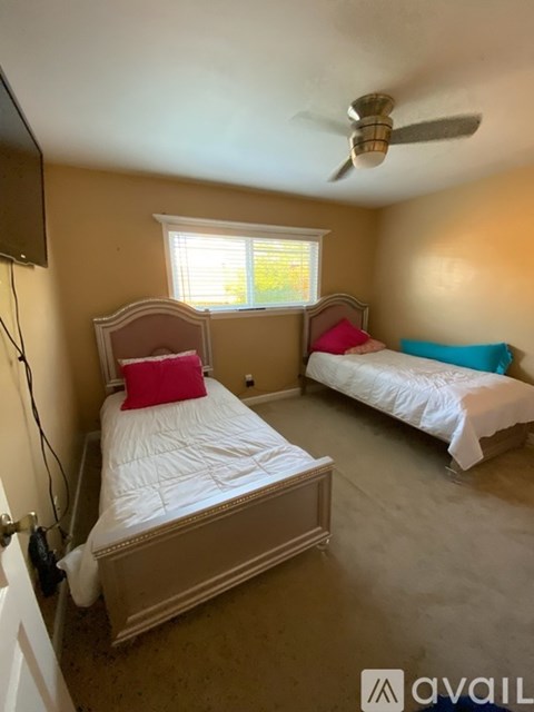 A bedroom with two beds and a ceiling fan.