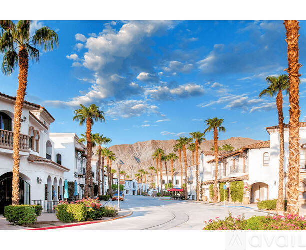 A street lined with palm trees and white buildings.