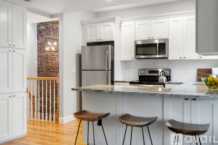 A kitchen with white cabinets and a brick wall.