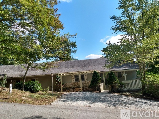 A house with a gravel driveway and trees in the background.